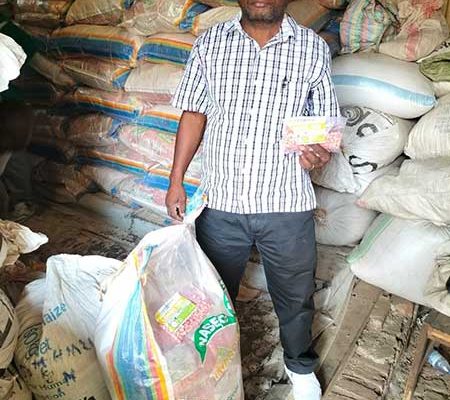 Herman Mutabataba, founder and director of Agriforce Seed Company, pictured here with small packs of hybrid maize procured from neighboring Uganda (Naseco Seed Company), facilitated by an AID-I GLR service provider partner, Seed Systems Group (SSG)
